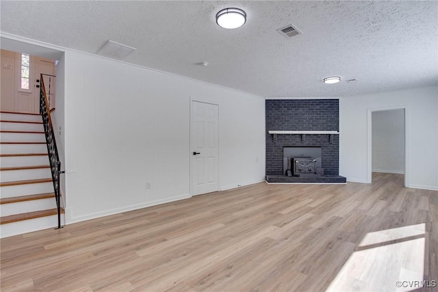 unfurnished living room with a brick fireplace, a textured ceiling, and light hardwood / wood-style floors