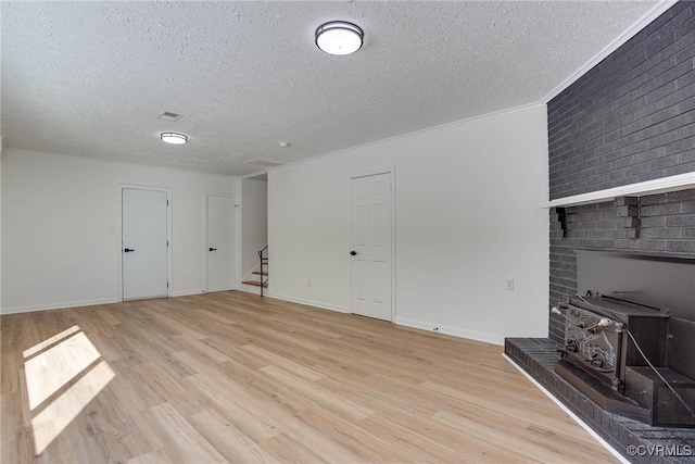 interior space with crown molding, a textured ceiling, light hardwood / wood-style flooring, and a wood stove