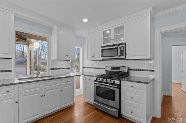 kitchen featuring white cabinetry, stainless steel appliances, decorative light fixtures, sink, and crown molding