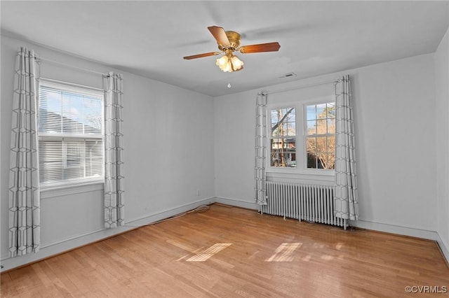 empty room with radiator heating unit, plenty of natural light, and wood-type flooring