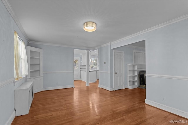 spare room with ornamental molding, plenty of natural light, ornate columns, and light hardwood / wood-style flooring