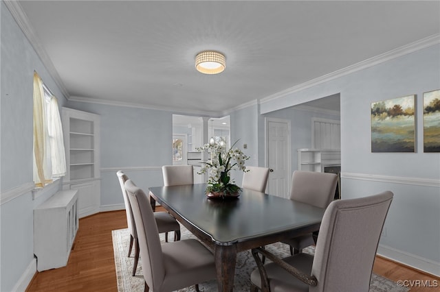 dining area featuring hardwood / wood-style flooring, crown molding, and decorative columns