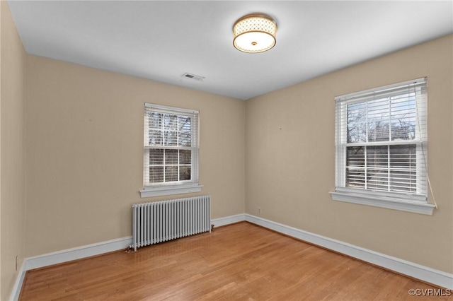 spare room with radiator heating unit and wood-type flooring