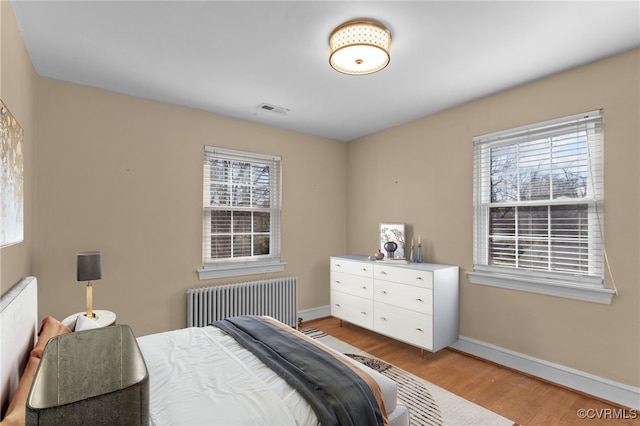 bedroom with light hardwood / wood-style flooring and radiator