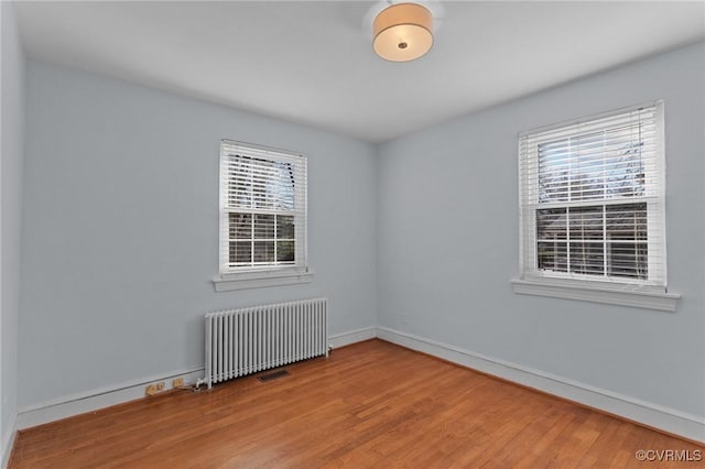 spare room featuring hardwood / wood-style floors and radiator heating unit