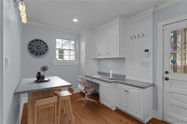 office area featuring crown molding, built in desk, and light hardwood / wood-style flooring