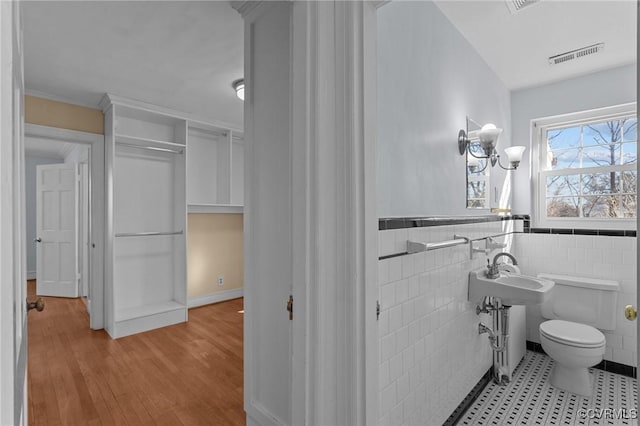 bathroom with toilet, tile walls, and hardwood / wood-style floors