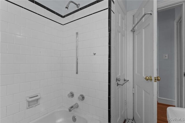 bathroom featuring wood-type flooring and tiled shower / bath