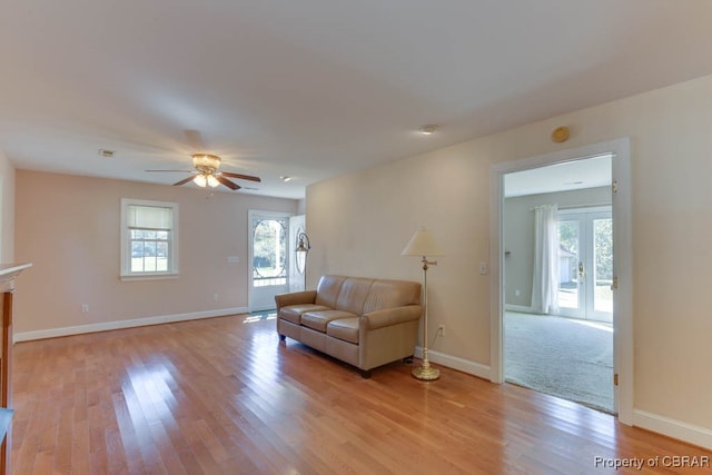 living room featuring french doors, light wood-type flooring, and ceiling fan