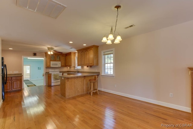 kitchen featuring light hardwood / wood-style floors, kitchen peninsula, sink, and white appliances