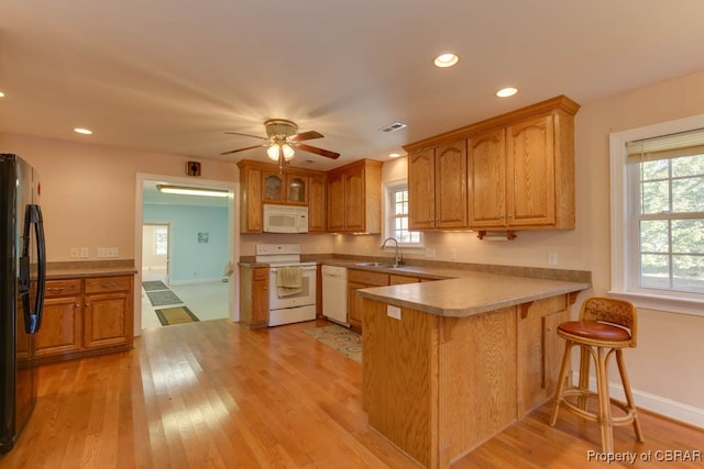 kitchen with kitchen peninsula, ceiling fan, light hardwood / wood-style floors, sink, and white appliances