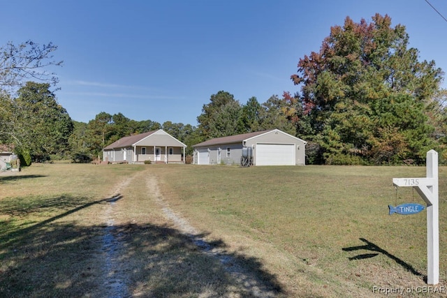 view of front of home featuring a garage, a front lawn, and an outdoor structure