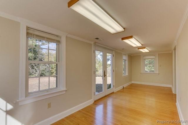 unfurnished room with crown molding, light hardwood / wood-style floors, and french doors