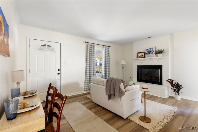 living room with a brick fireplace and wood-type flooring