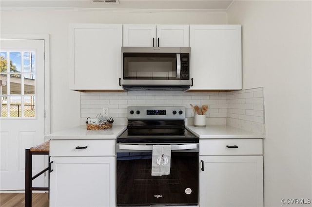 kitchen with hardwood / wood-style flooring, range with electric stovetop, backsplash, ornamental molding, and white cabinetry