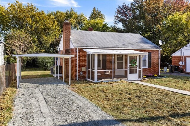 bungalow with a front lawn, a sunroom, and a carport