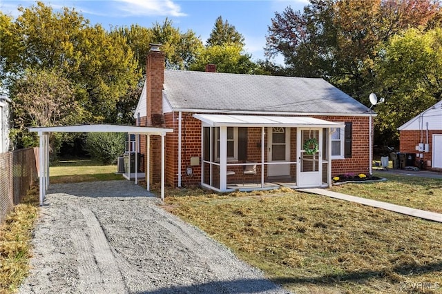 bungalow-style home featuring a sunroom, a front yard, and a carport