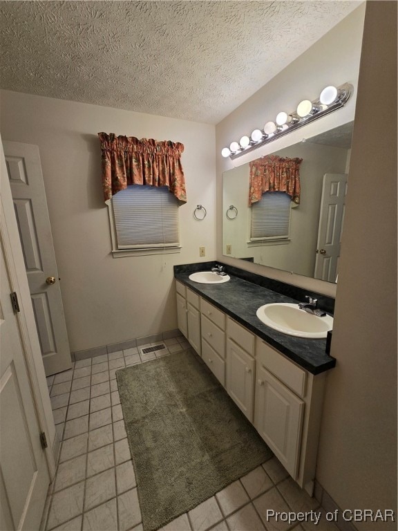 bathroom with vanity, a textured ceiling, and tile patterned flooring