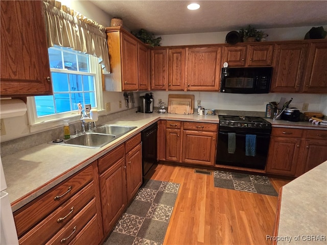 kitchen featuring sink, black appliances, and light hardwood / wood-style floors