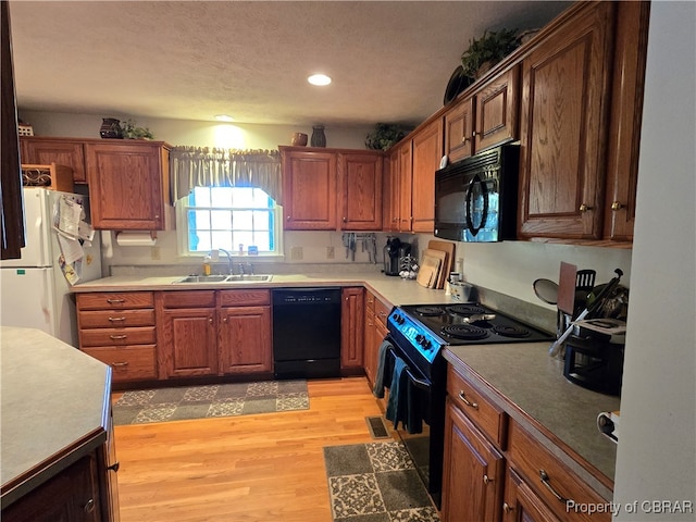 kitchen featuring light hardwood / wood-style floors, a textured ceiling, black appliances, and sink