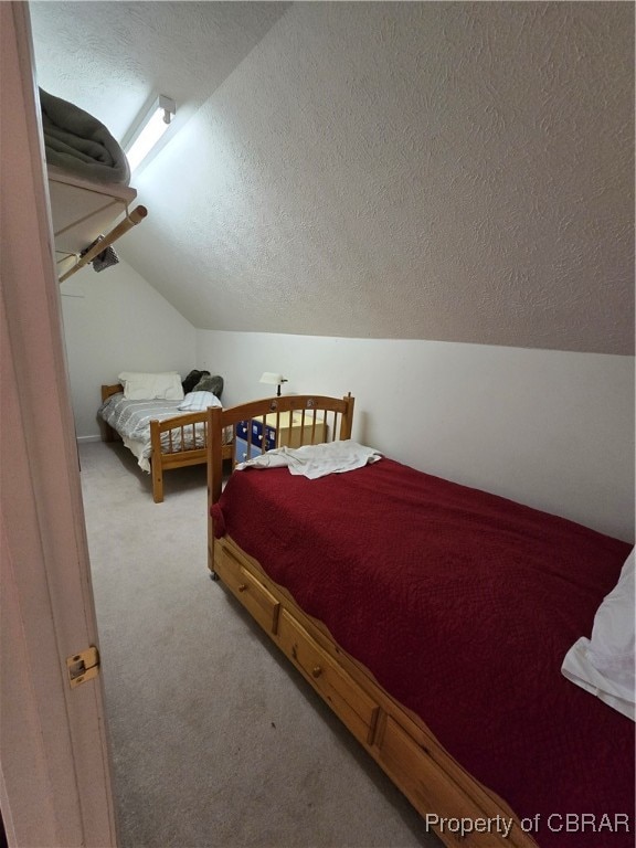 bedroom with a textured ceiling, carpet flooring, and vaulted ceiling