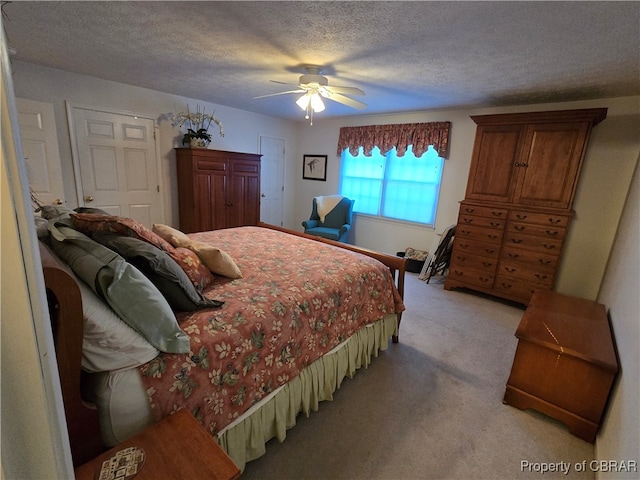 carpeted bedroom with ceiling fan and a textured ceiling