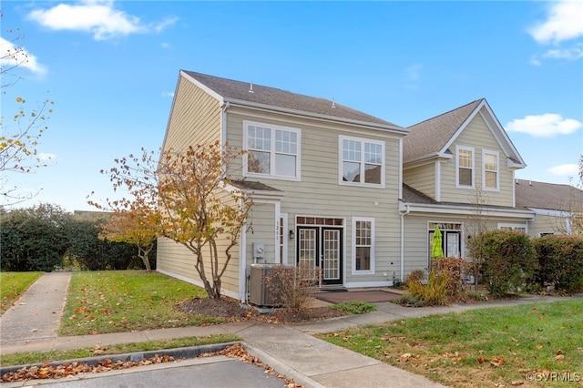 view of front of house with central AC and a front yard