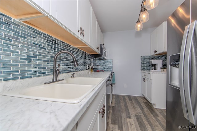 kitchen featuring sink, decorative light fixtures, white cabinets, stainless steel appliances, and backsplash