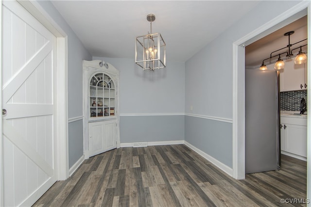 unfurnished dining area featuring sink, dark hardwood / wood-style floors, and a chandelier