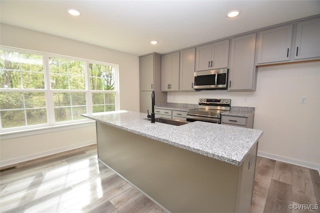 kitchen with plenty of natural light, gray cabinets, stainless steel appliances, and a sink