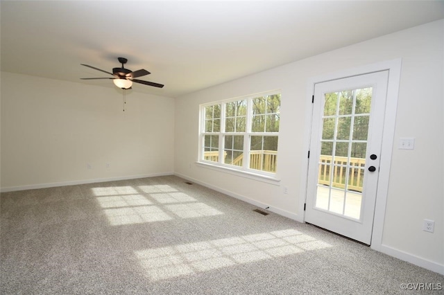 carpeted spare room featuring a ceiling fan, visible vents, and baseboards