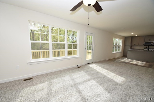 unfurnished living room with recessed lighting, light colored carpet, a ceiling fan, baseboards, and visible vents