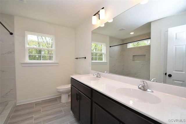 bathroom featuring vanity, tiled shower, and toilet