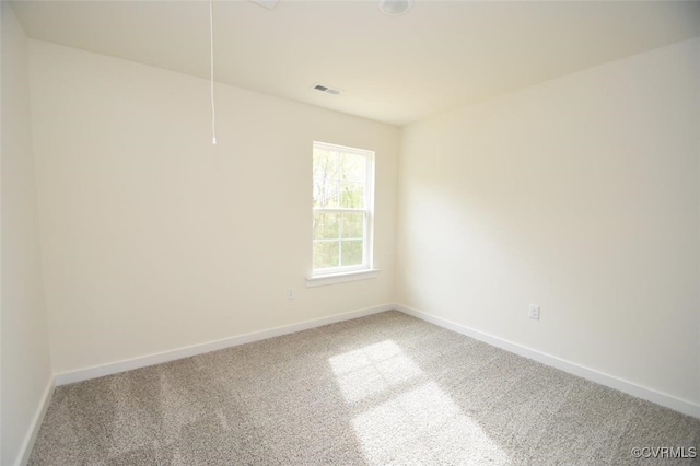 carpeted empty room featuring attic access, visible vents, and baseboards