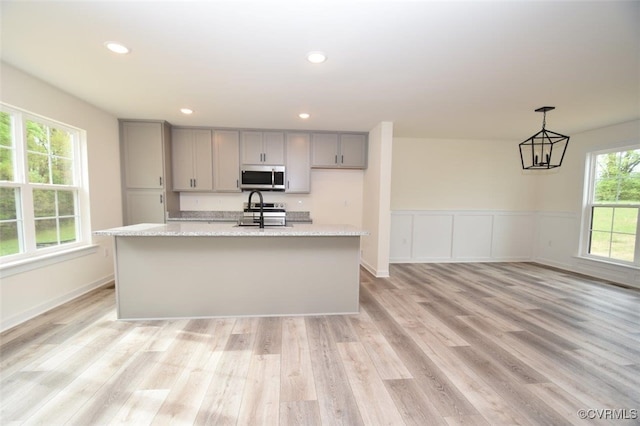 kitchen with light wood-style flooring, a kitchen island with sink, appliances with stainless steel finishes, and gray cabinetry