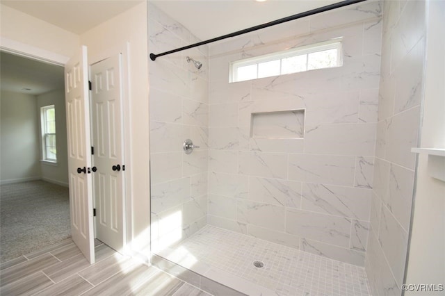 full bathroom with a tile shower and baseboards