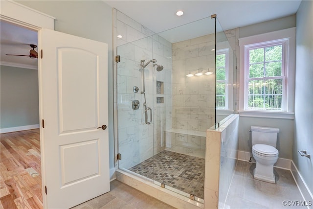 bathroom featuring toilet, a shower with shower door, ornamental molding, hardwood / wood-style floors, and ceiling fan