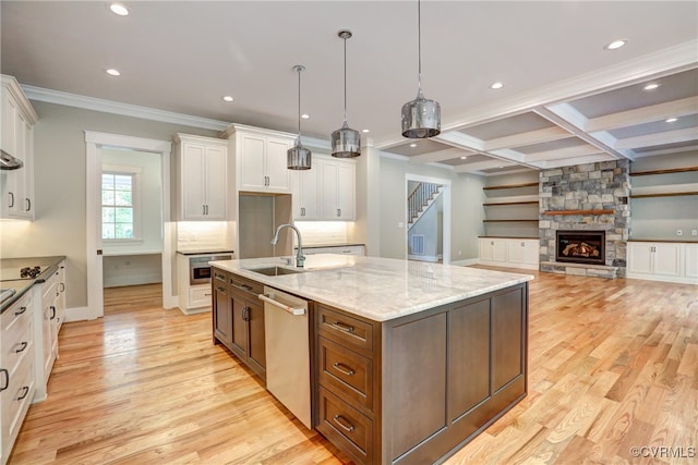 kitchen featuring dishwasher, a fireplace, pendant lighting, white cabinets, and a center island with sink