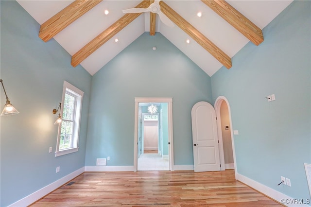 unfurnished living room featuring light hardwood / wood-style flooring, beam ceiling, and high vaulted ceiling