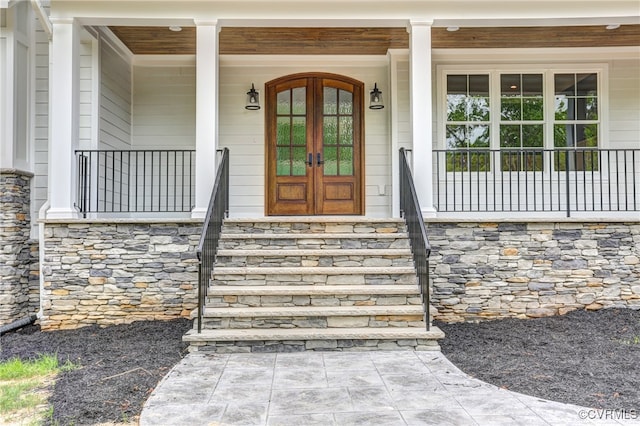 view of exterior entry featuring french doors and covered porch