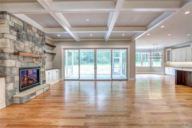 unfurnished living room with a chandelier, a fireplace, light hardwood / wood-style floors, crown molding, and coffered ceiling