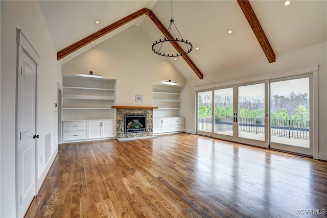 unfurnished living room with beam ceiling, high vaulted ceiling, wood-type flooring, and a stone fireplace