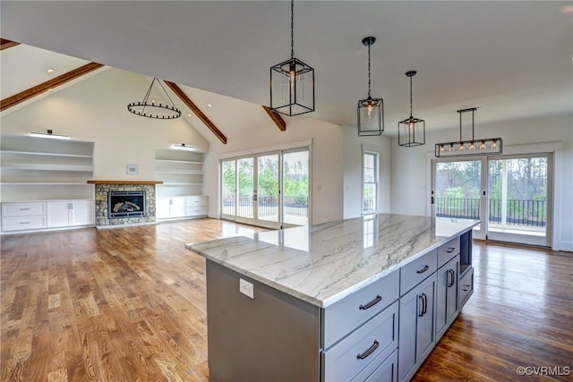 kitchen with hardwood / wood-style flooring, a center island, a fireplace, and hanging light fixtures