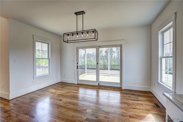 unfurnished dining area with hardwood / wood-style flooring and an inviting chandelier