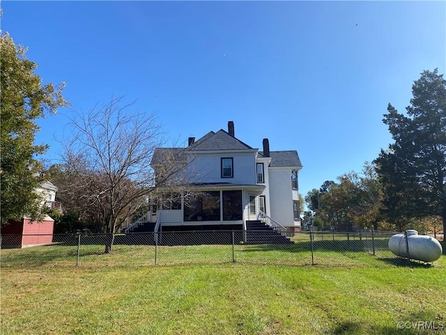 rear view of house with a fenced backyard and a lawn
