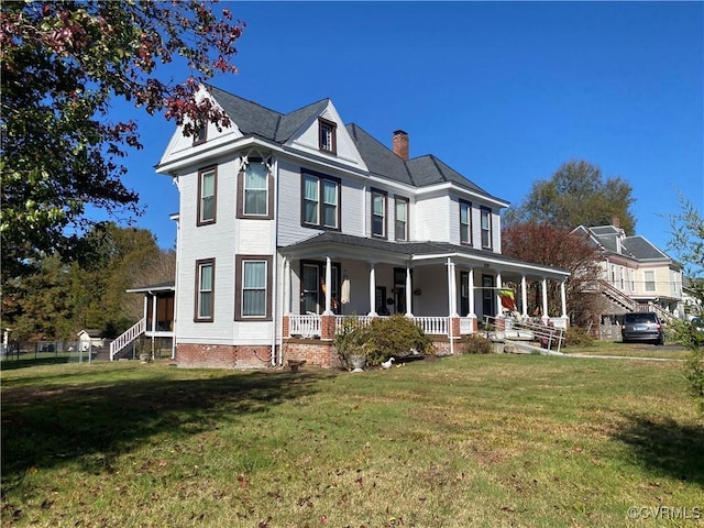 victorian-style house featuring a front yard, covered porch, and a chimney