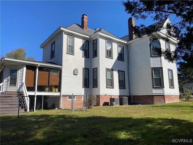 rear view of property with a sunroom, cooling unit, and a yard