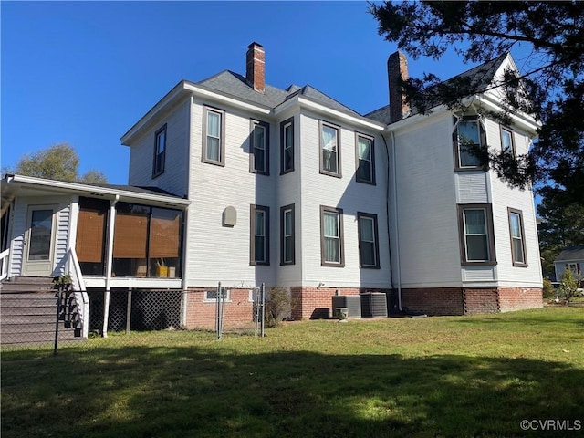 back of property featuring a yard, central AC unit, a sunroom, and a chimney