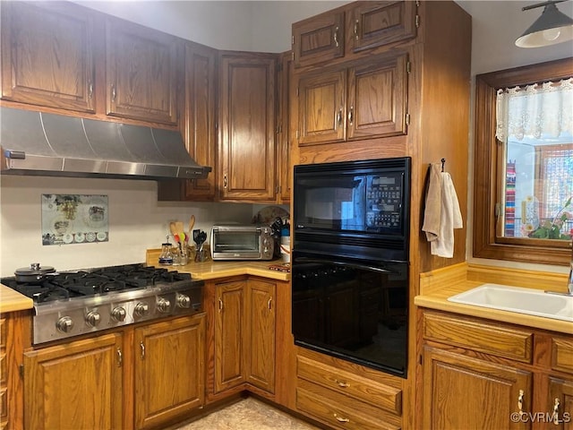 kitchen featuring under cabinet range hood, a sink, light countertops, and black appliances