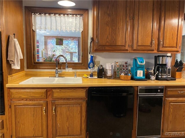 kitchen featuring brown cabinetry, dishwasher, light countertops, and a sink